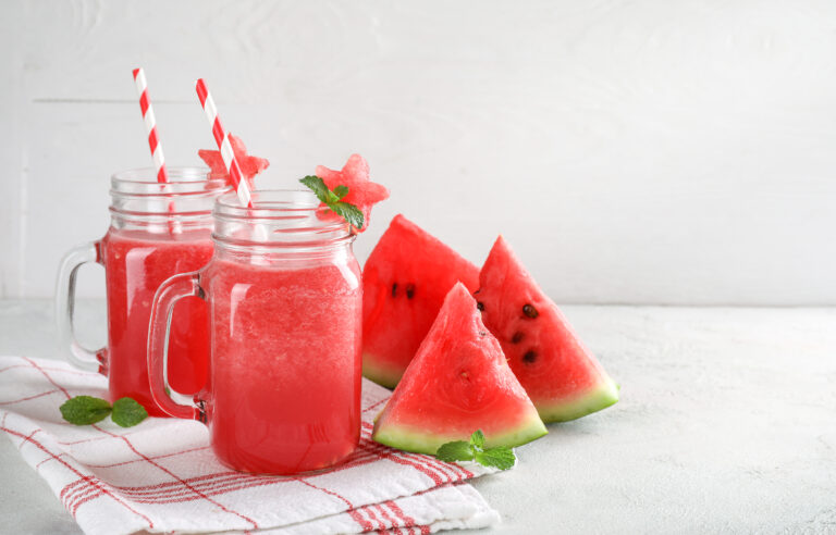 Fresh tasty watermelon smoothie in glass jars on white background.